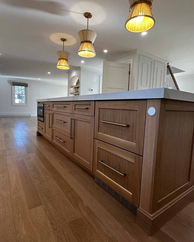 Wooden kitchen island with drawers, a countertop, and pendant lights. Hardwood floor.