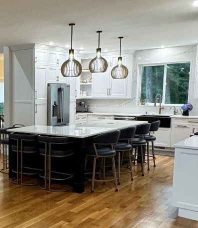 Modern kitchen with a black island, white countertops, and three pendant lights.