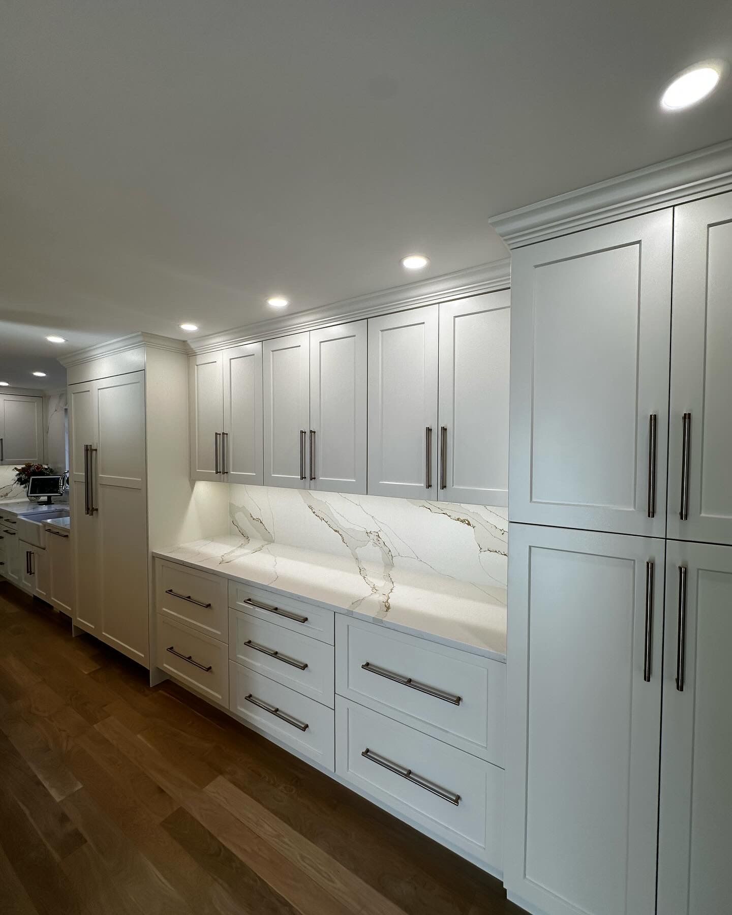 White kitchen cabinets with light-colored countertops and hardwood floor.