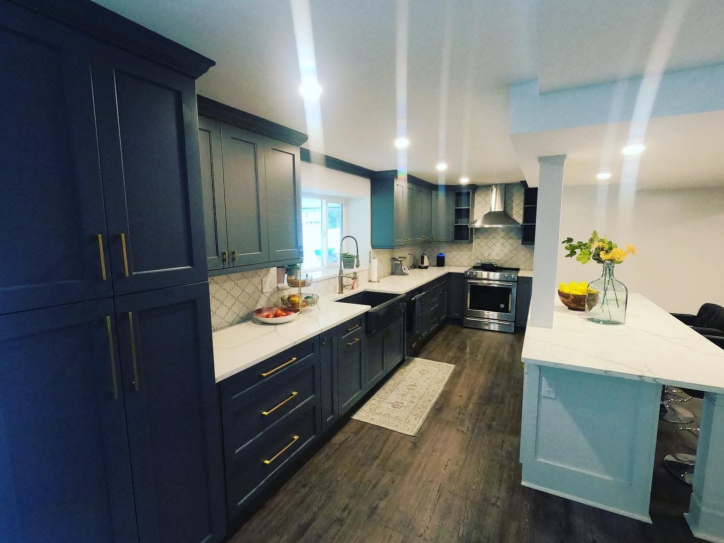 Modern kitchen with blue cabinets, white countertops, and wooden floors.