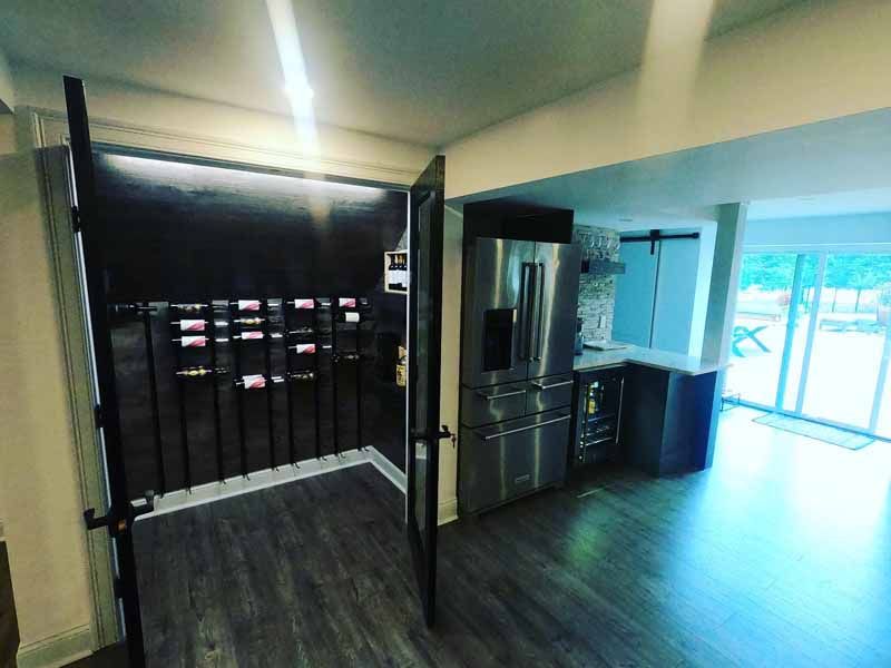 Wine cellar with bottles displayed, stainless steel refrigerator, and modern kitchen.