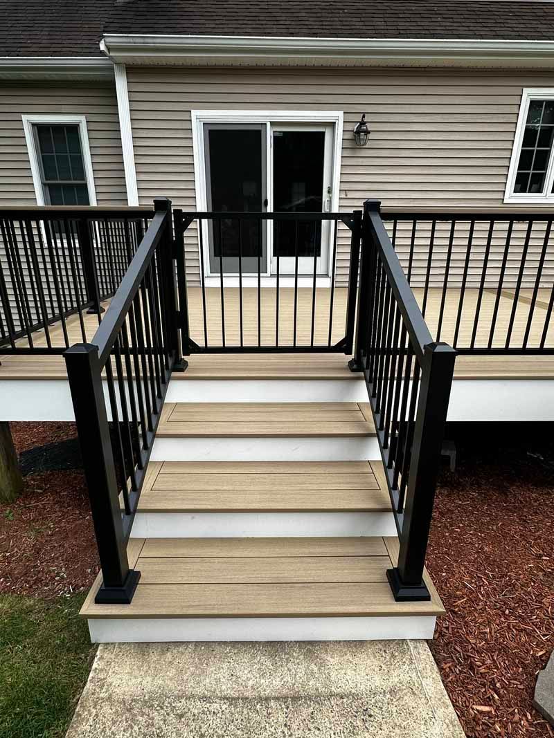 Deck stairs with black railing and gate, leading to a sliding glass door.