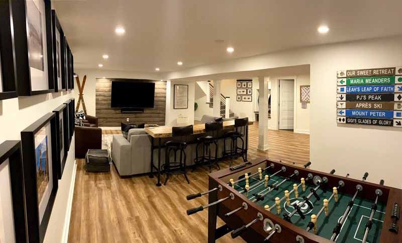 Basement recreation room with foosball table, bar, TV, and framed artwork.