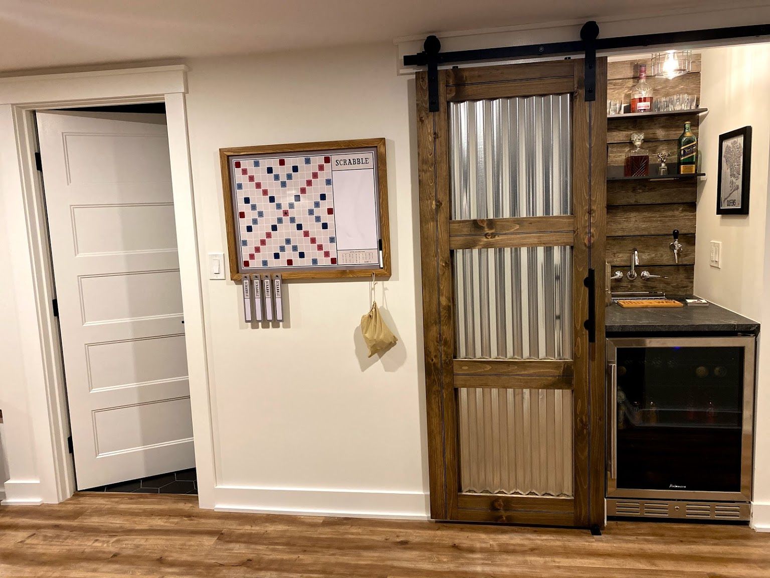 Basement bar area with a sliding barn door, dartboard, and mini-fridge.