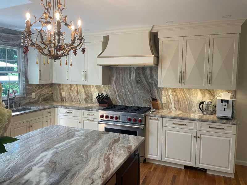 Kitchen with white cabinets, marble countertops, stainless steel appliances, and a chandelier.
