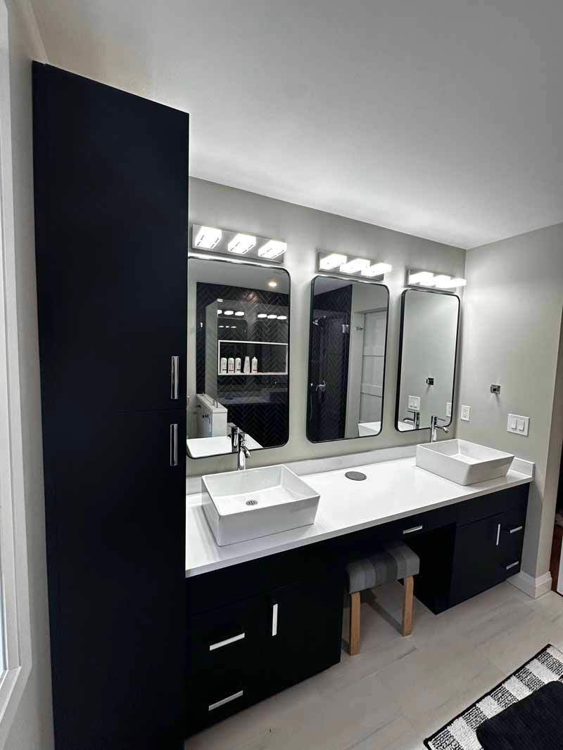Black and white bathroom vanity with vessel sinks, mirrors, and storage cabinet.