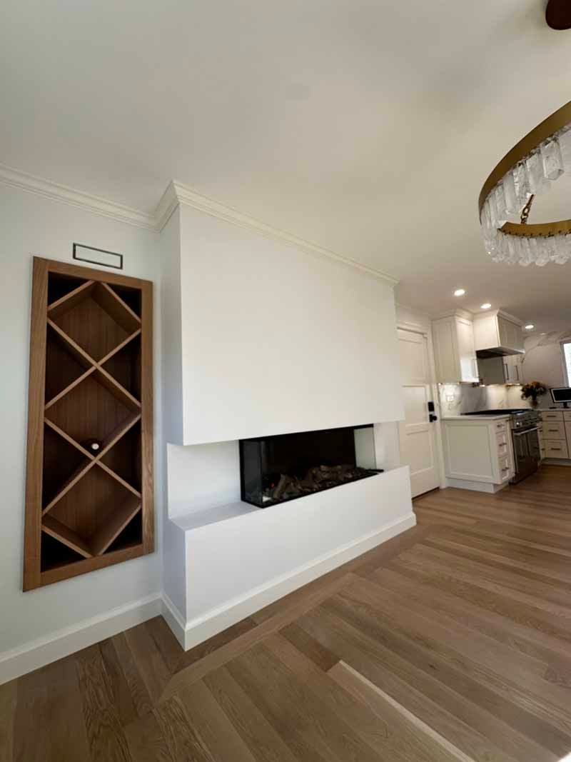 Modern living room with fireplace, built-in wine rack, and light wood flooring.