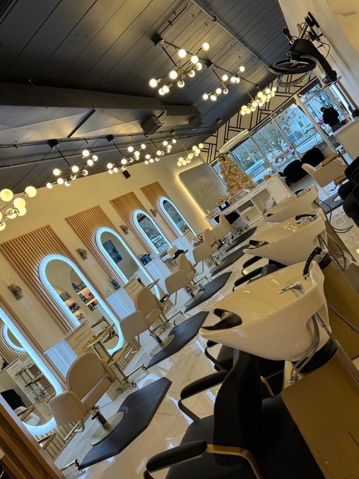Salon interior with hair styling stations, mirrors, and lighting fixtures.