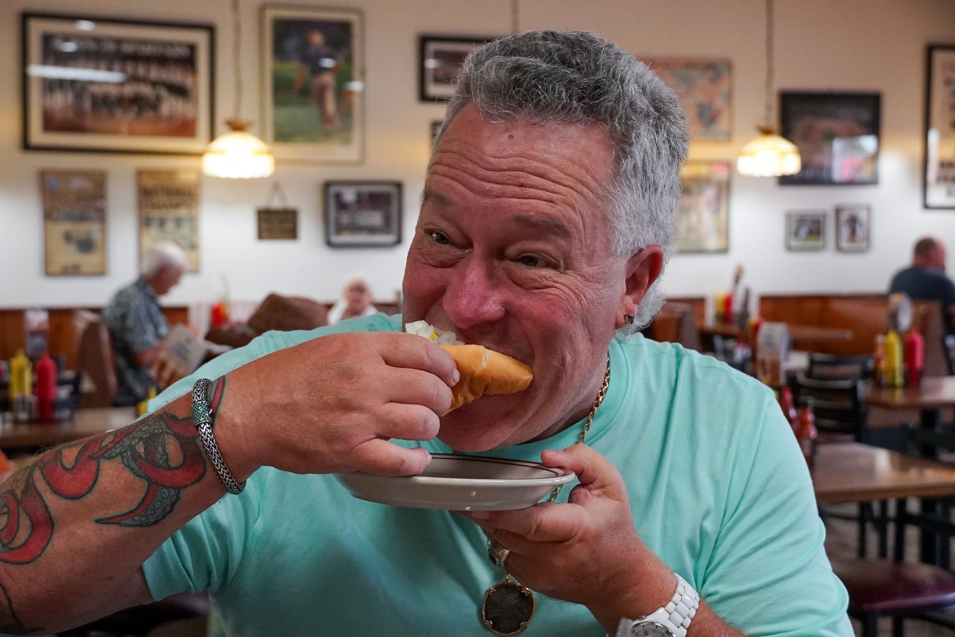 A man is eating a hot dog in a restaurant.