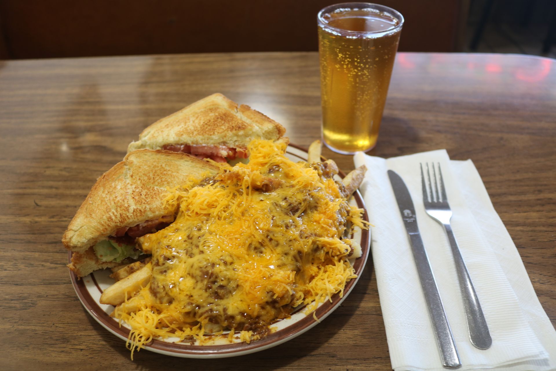 A plate of food and a glass of beer on a table.