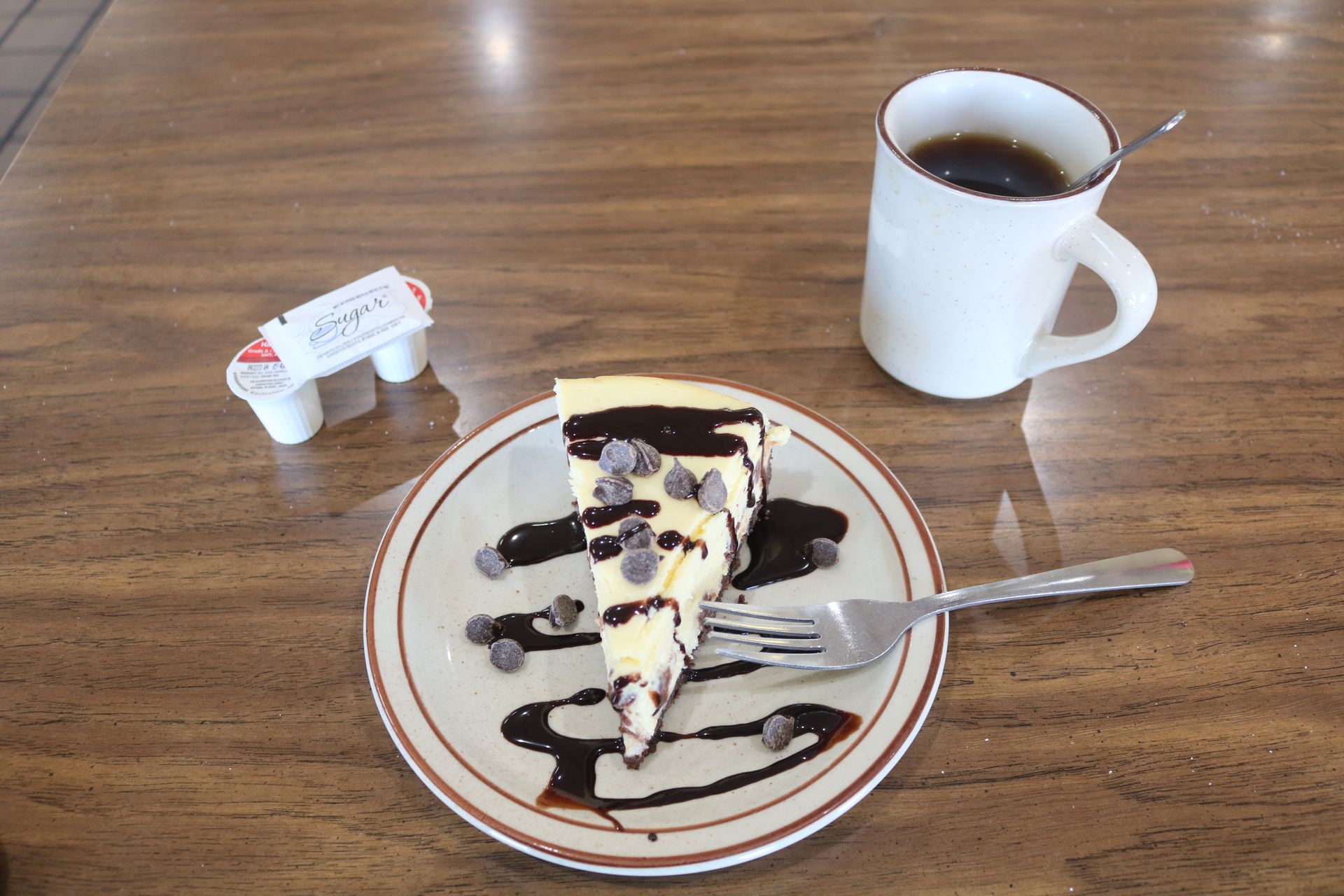 A slice of cheesecake on a plate next to a cup of coffee