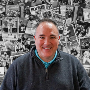 A man is smiling in front of a wall with pictures of football players and the word rookie on it