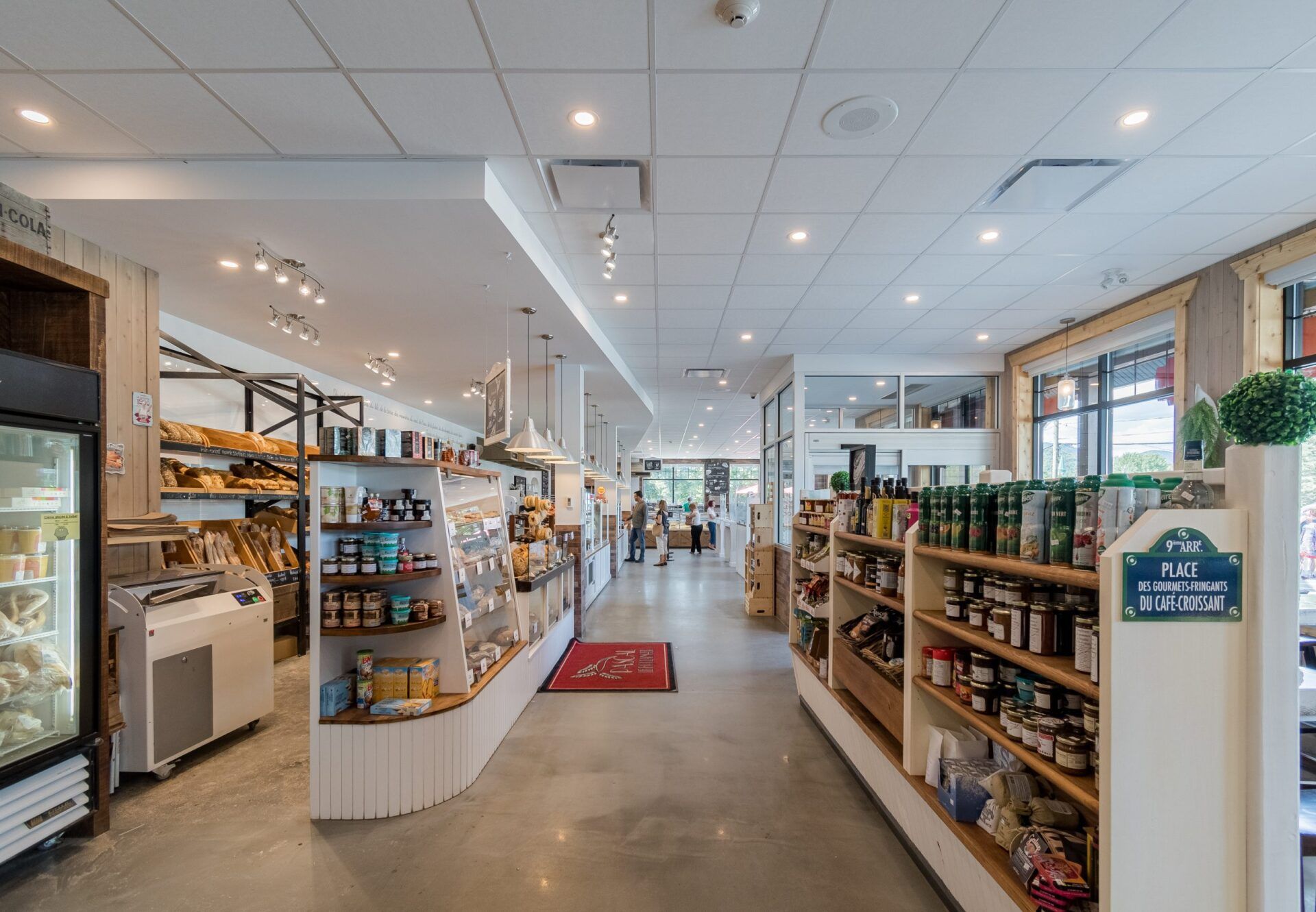 Vue intérieure d'une épicerie bien éclairée, avec des étagères remplies de produits et une allée centrale.