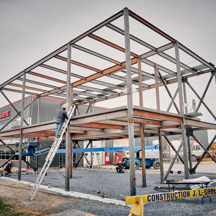 Chantier de construction à ossature métallique avec des ouvriers sur des échelles et dans un ascenseur. Bâtiment en construction.
