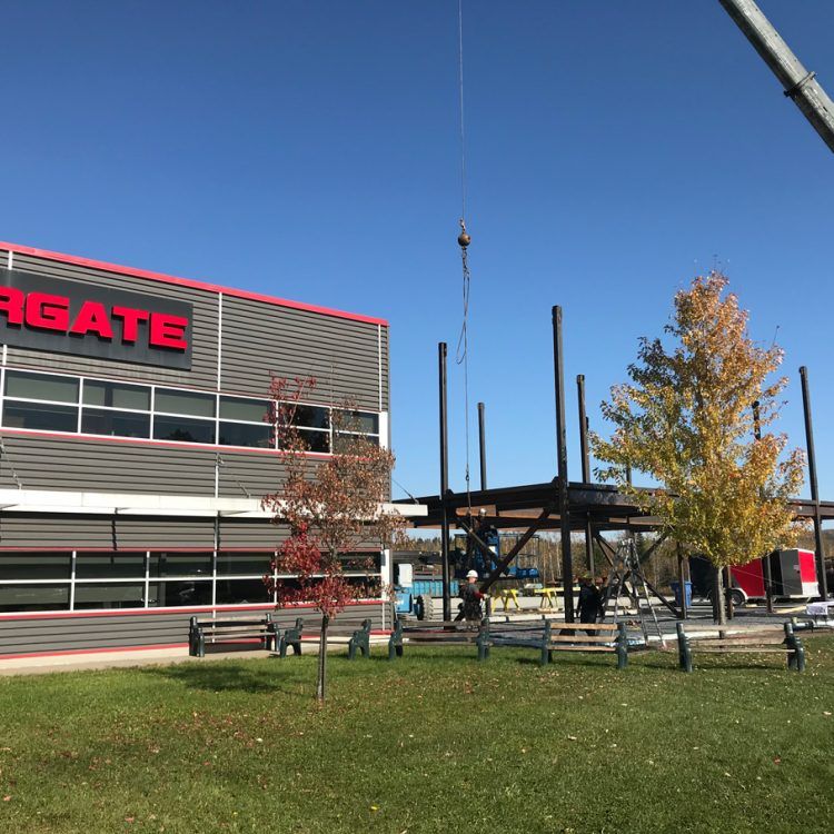 Construction d'une structure en acier près d'un bâtiment portant l'enseigne « ARGATE », sous un ciel bleu.