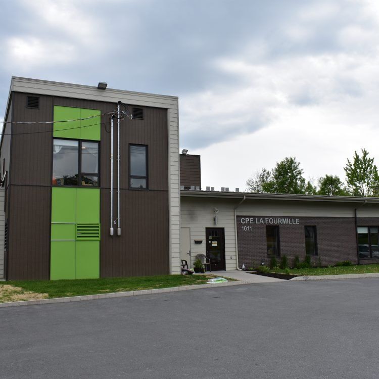 Bâtiment brun et vert avec une enseigne indiquant « CPE LA FONTAINEVILLE 1075 ». Ciel nuageux.