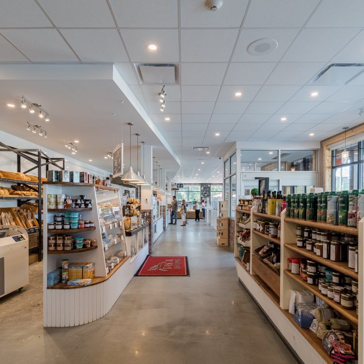 Intérieur d'un magasin d'alimentation spécialisé, avec des étagères remplies de produits et des clients près de l'entrée.