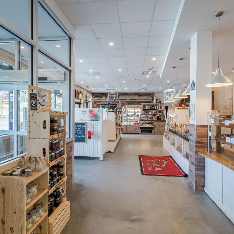 Intérieur d'un magasin, présentant des étagères avec des bocaux et des produits alimentaires, avec des éléments en bois et un éclairage vif.