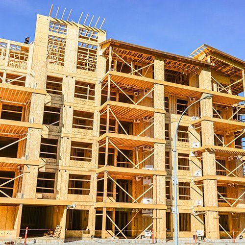 Bâtiment à ossature bois de plusieurs étages en construction ; ciel bleu en arrière-plan.
