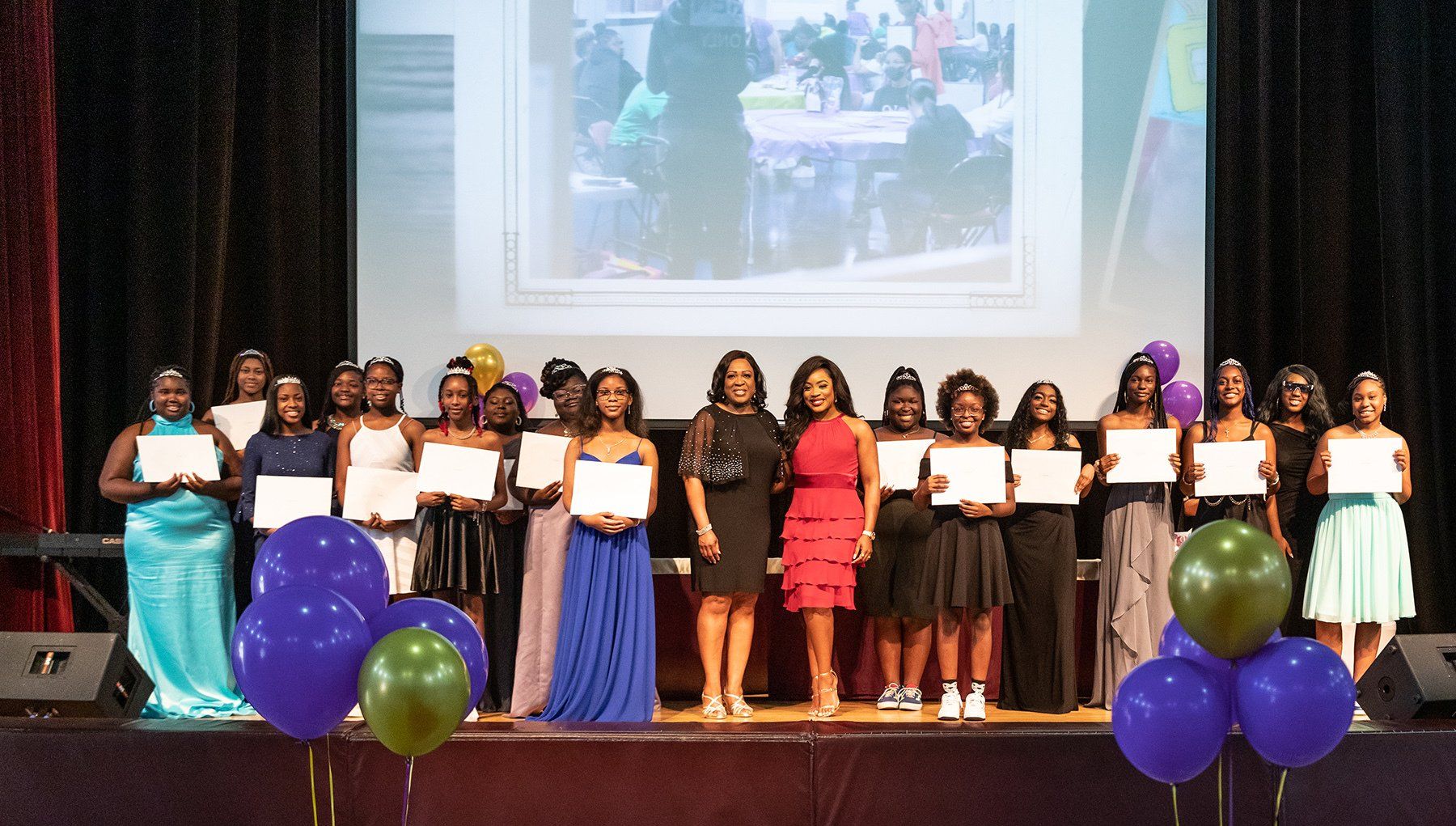 a group of girls standing on a stage holding certificates