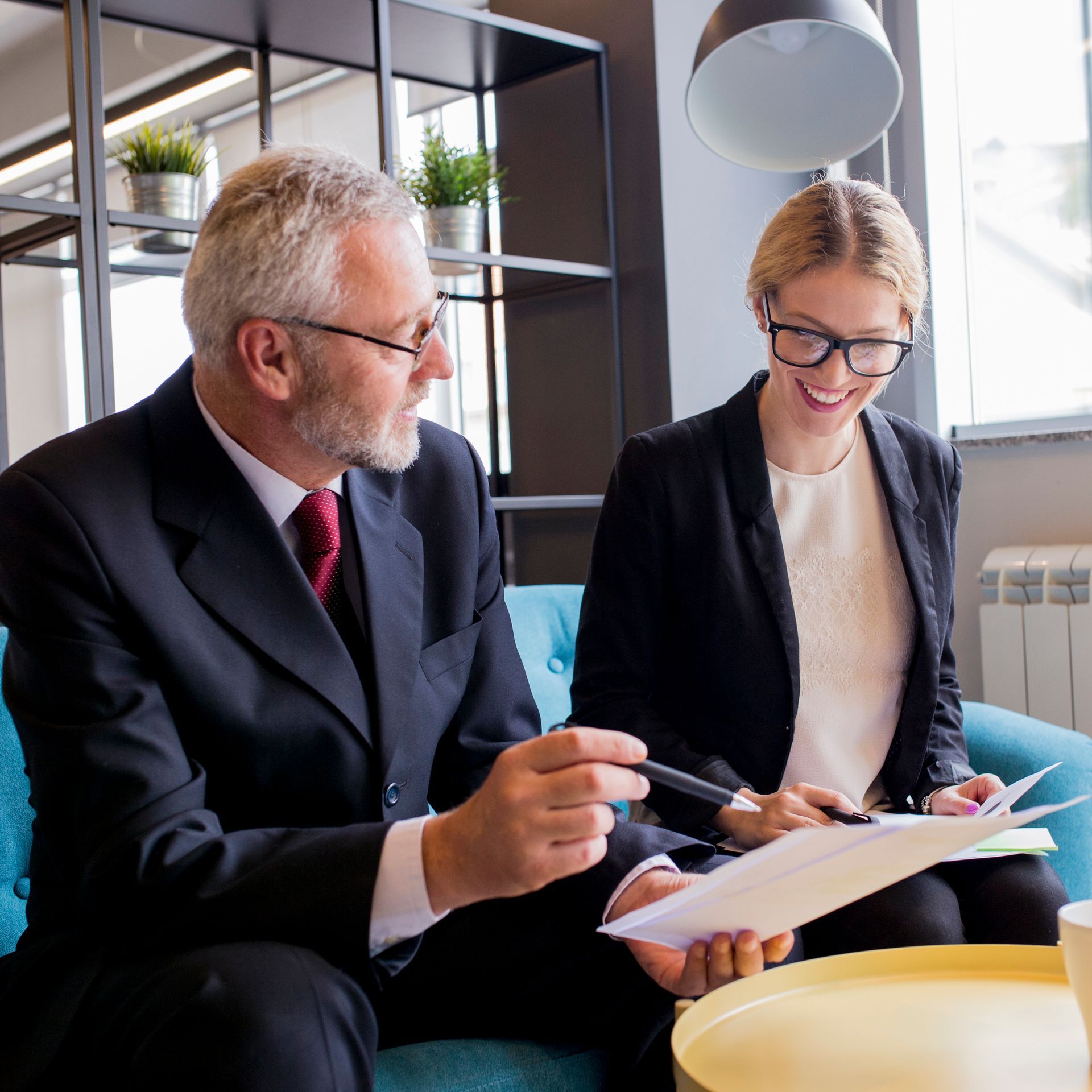 A man and a woman are sitting on a couch looking at papers.