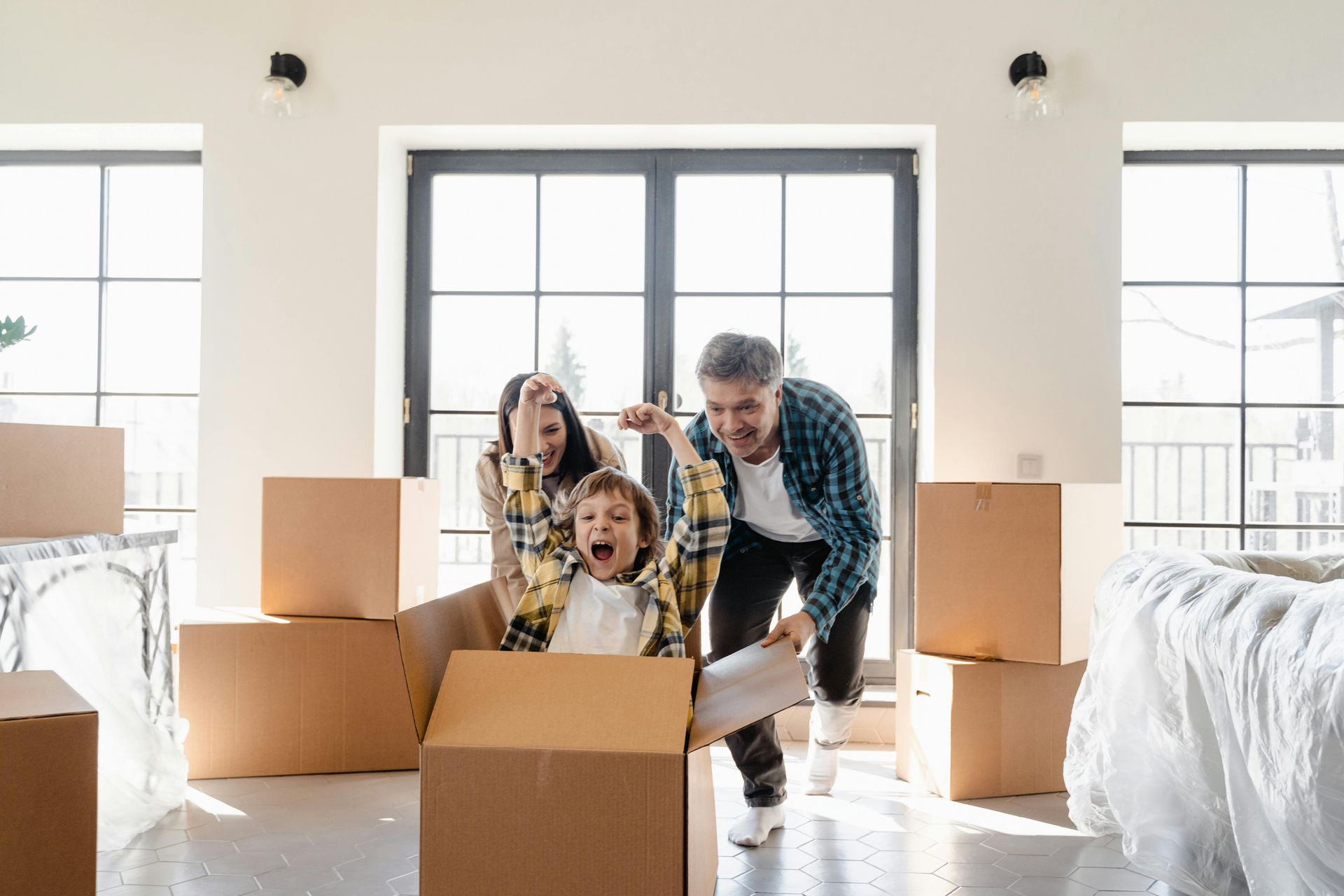 A family is playing in a cardboard box in a new home.