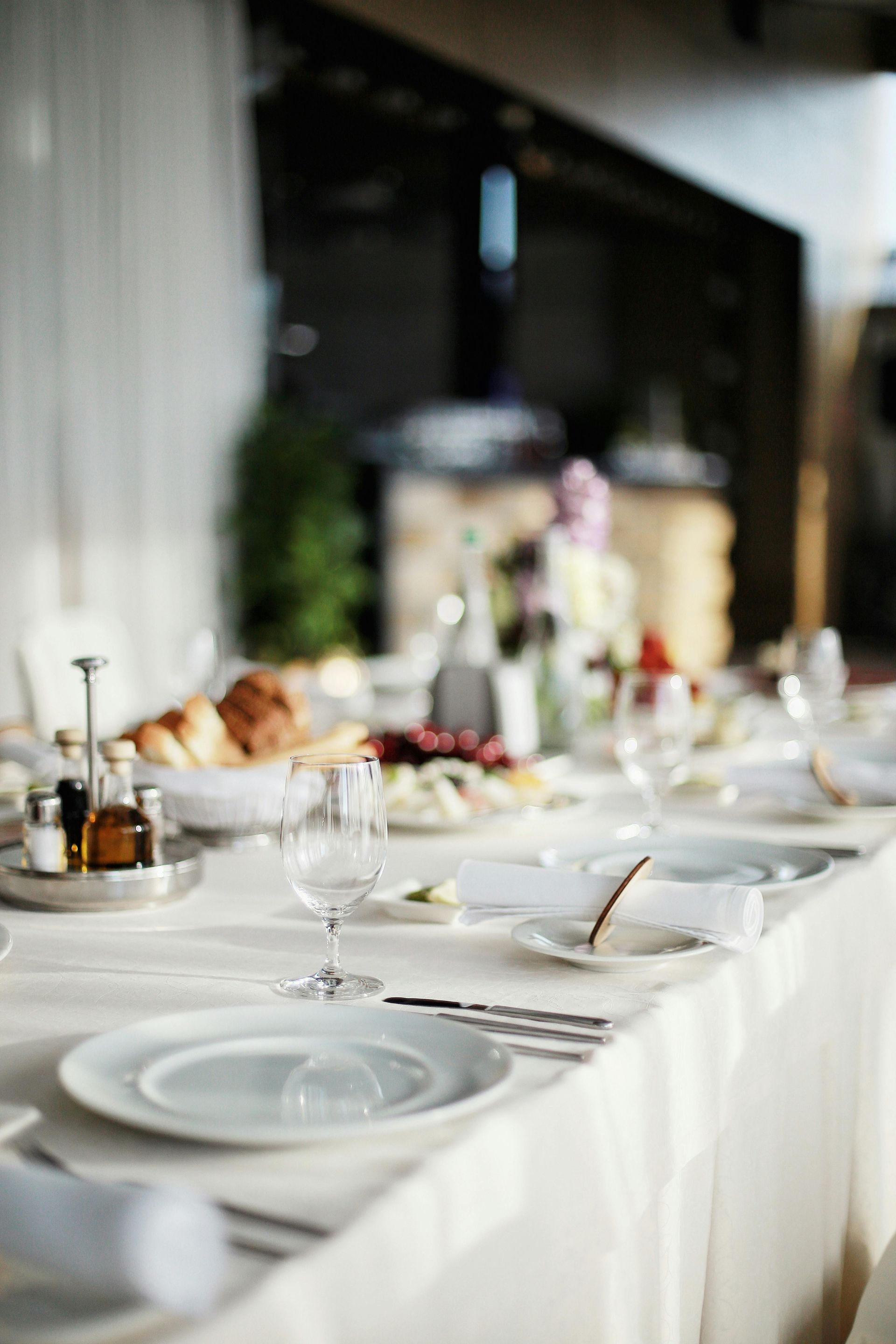 A long table with plates , glasses , and silverware on it.