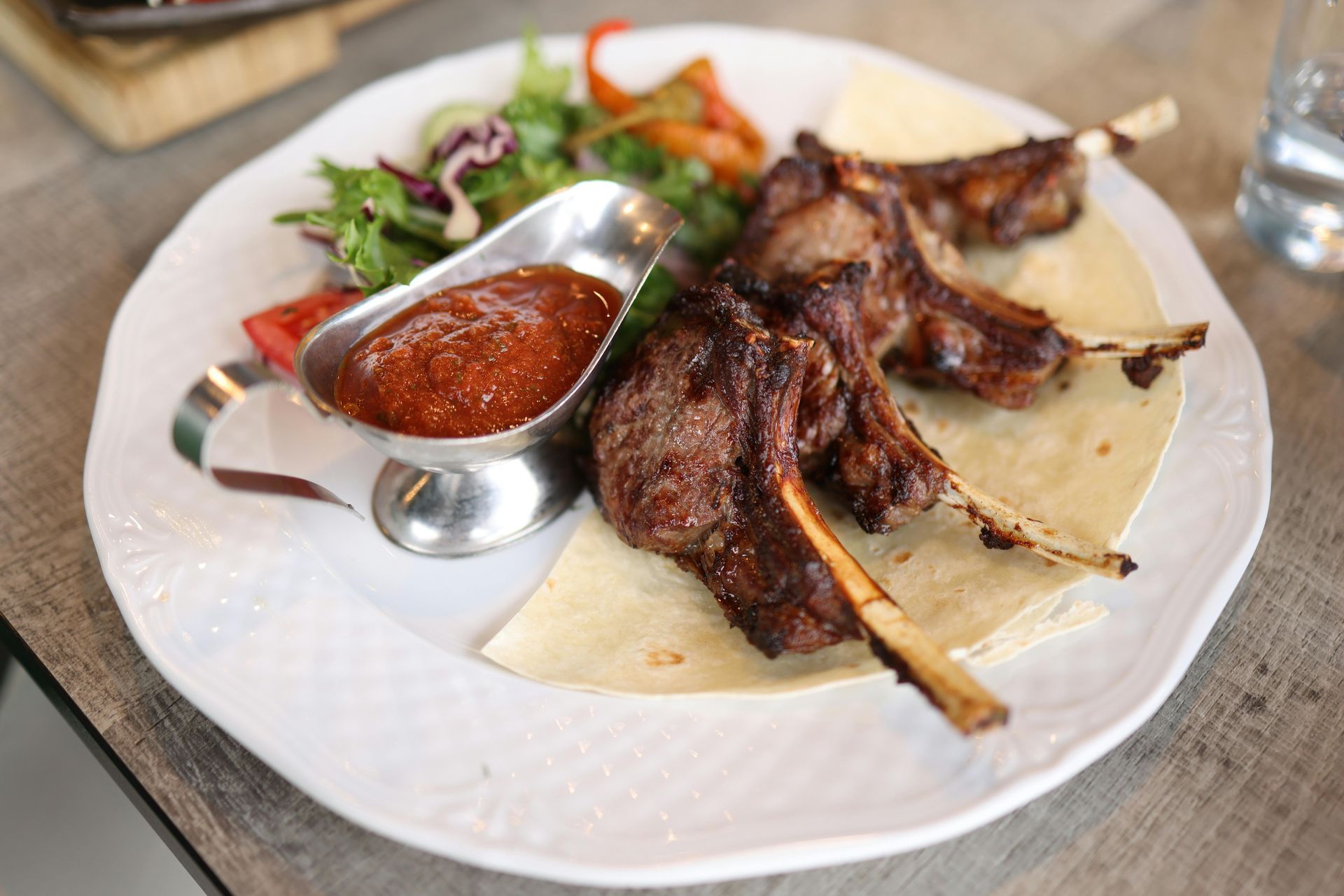 A white plate topped with meat and sauce on a table.