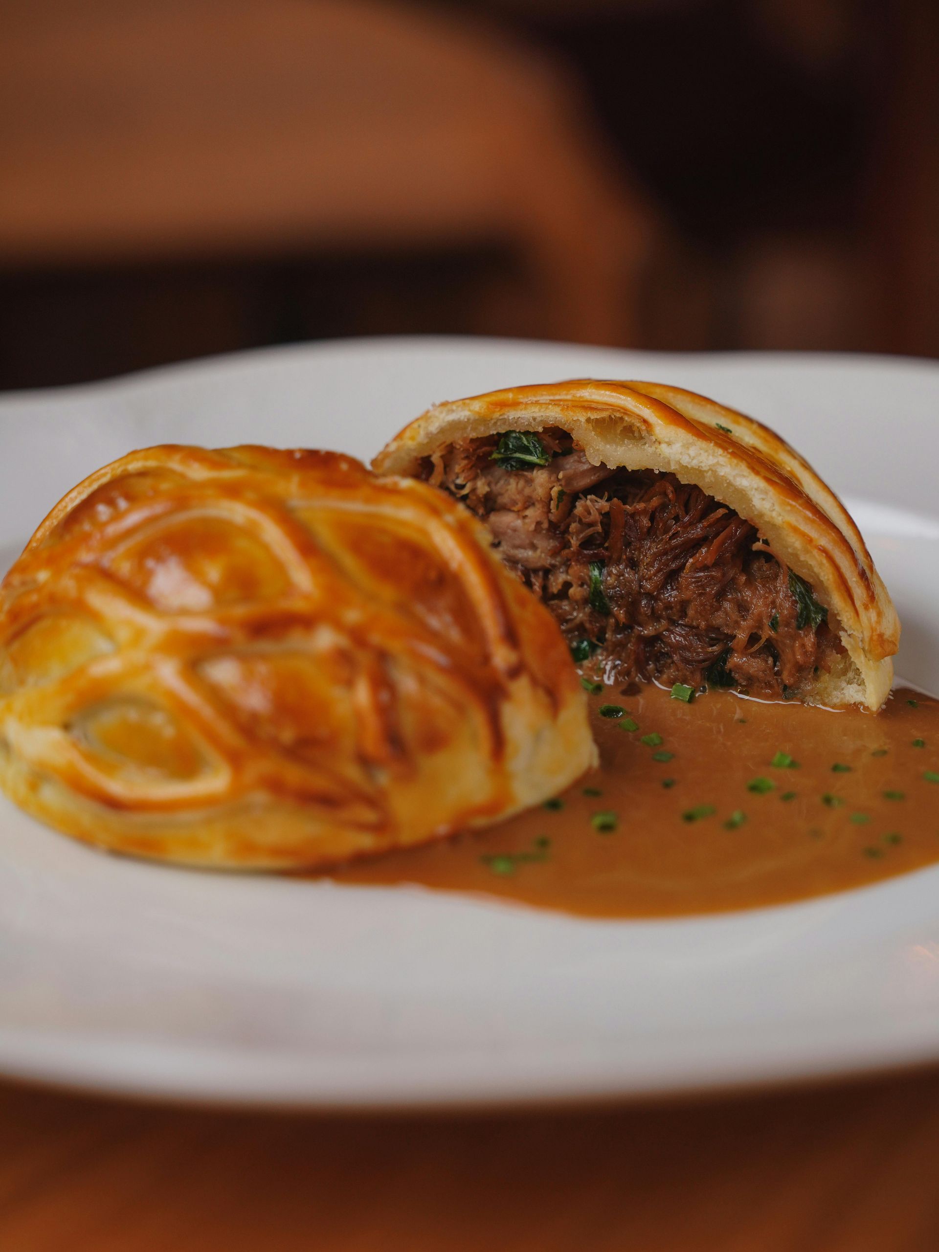 A pastry with meat and sauce on a white plate.