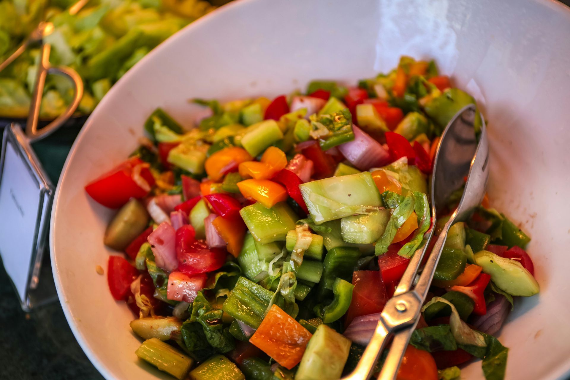 A bowl of salad with a spoon and fork in it