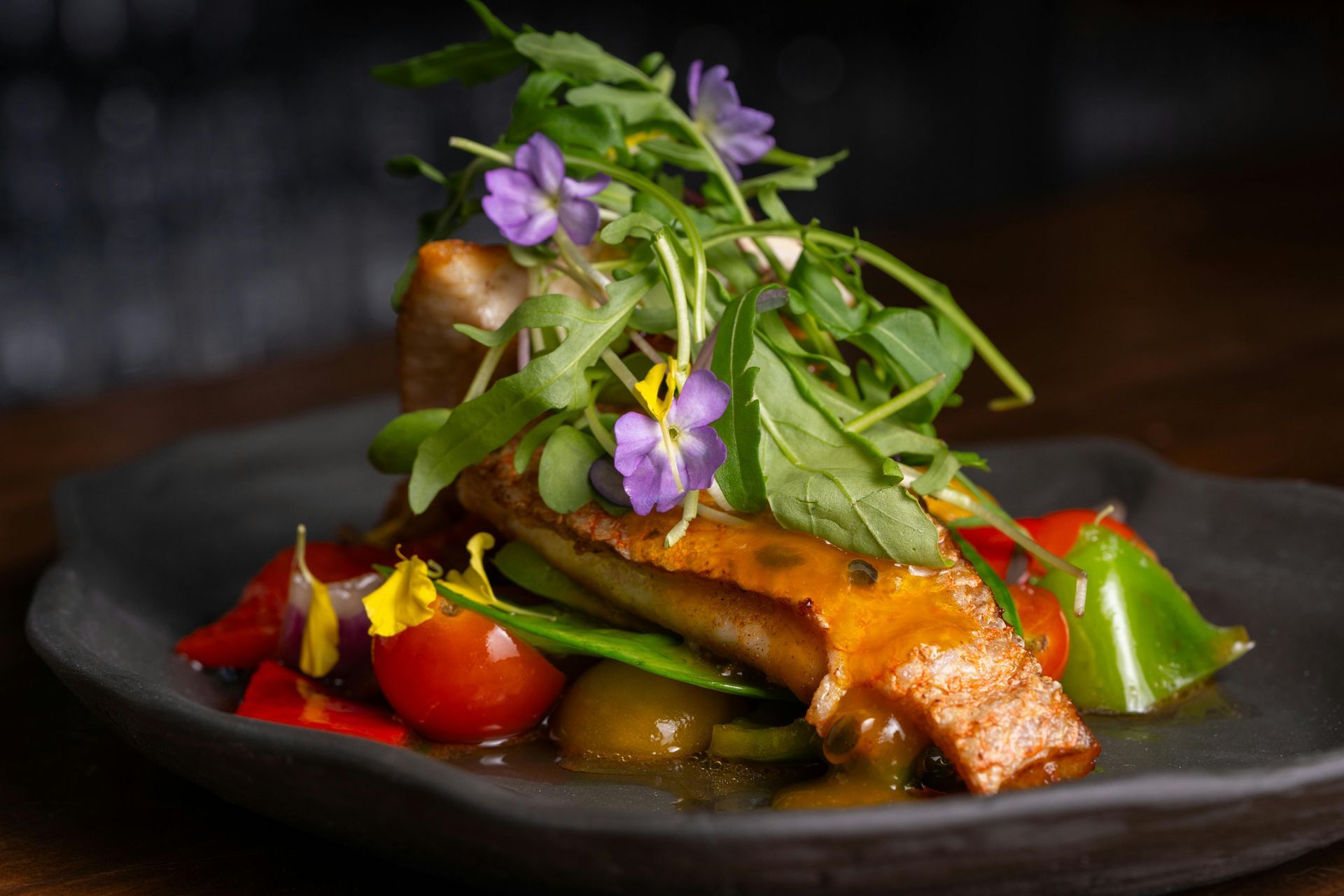 A close up of a plate of food with vegetables and flowers on a table.