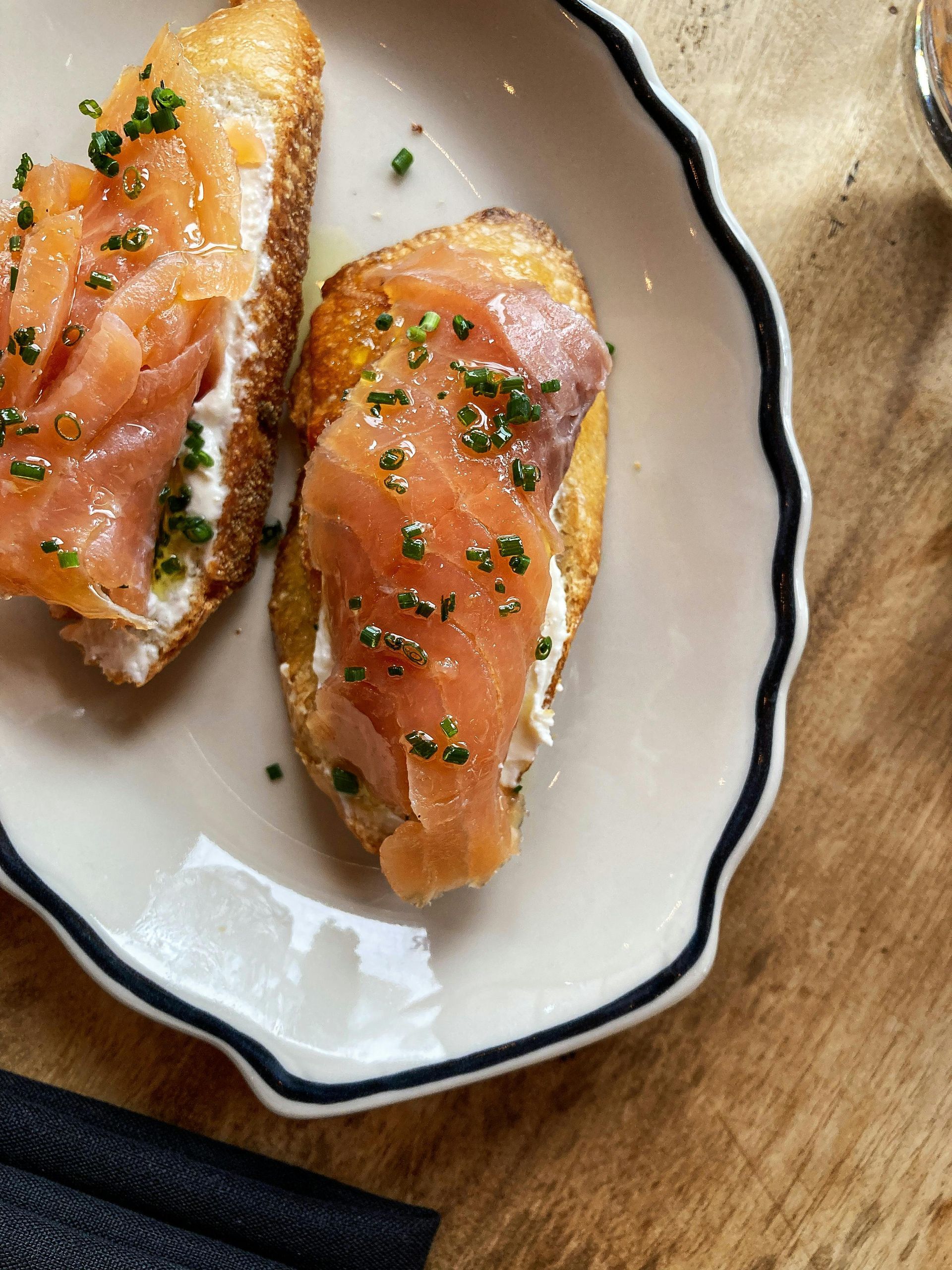 A white plate topped with two sandwiches with smoked salmon and cheese