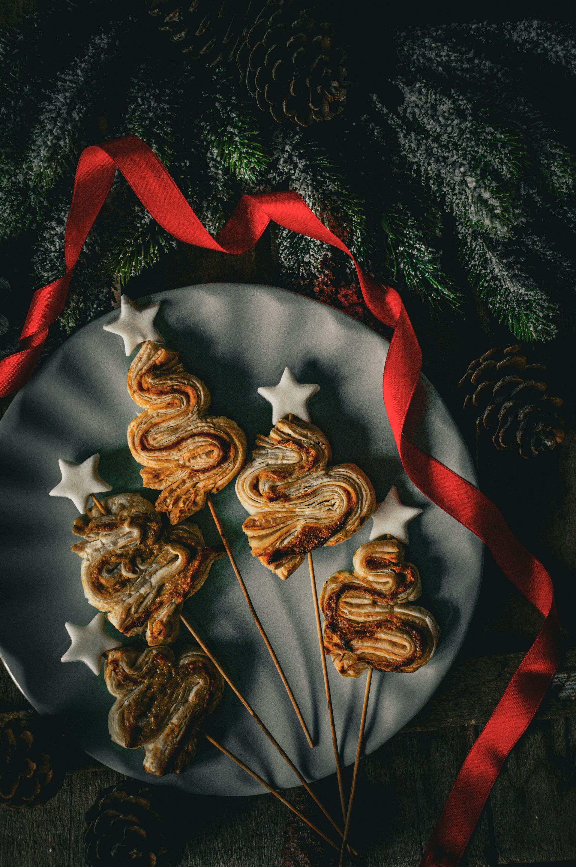 A white plate topped with christmas tree shaped cookies on sticks.