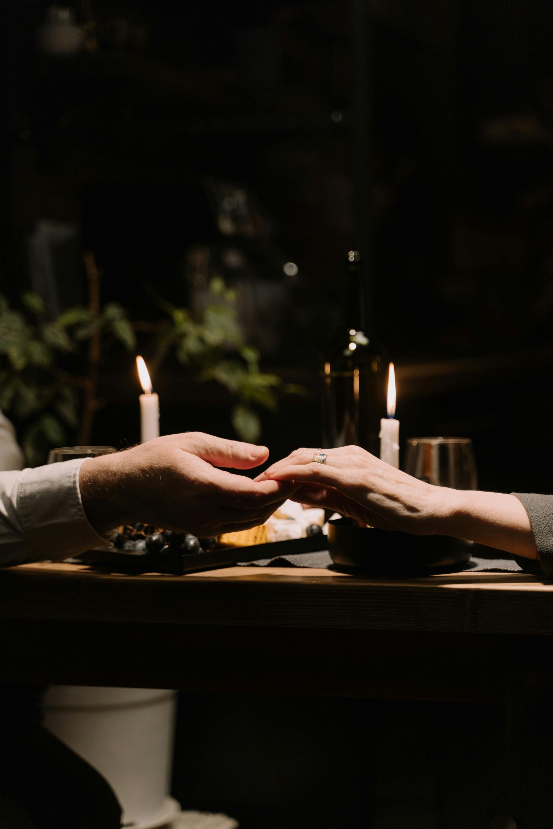 A man and a woman are holding hands at a table with candles.