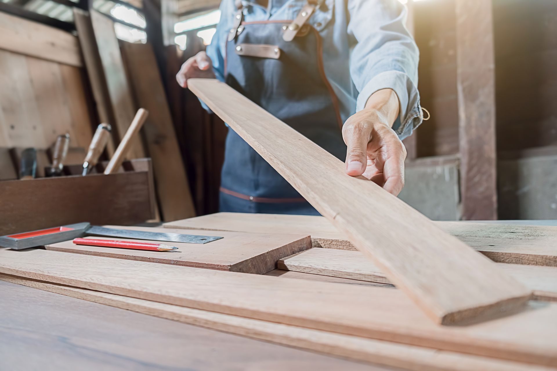 A carpenter working with building material on a wooden table at a carpentry shop.