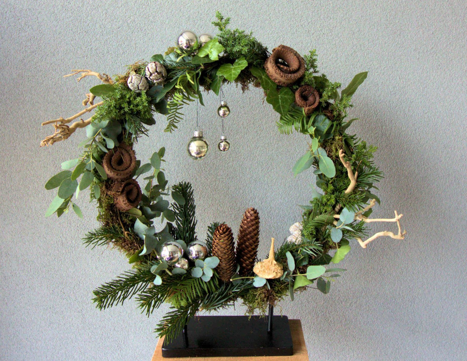 Een kerstkrans zit op een houten standaard
