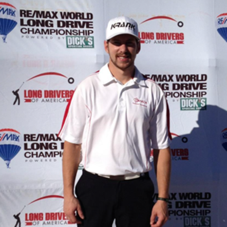 A man stands in front of a re/max world long drive championship banner