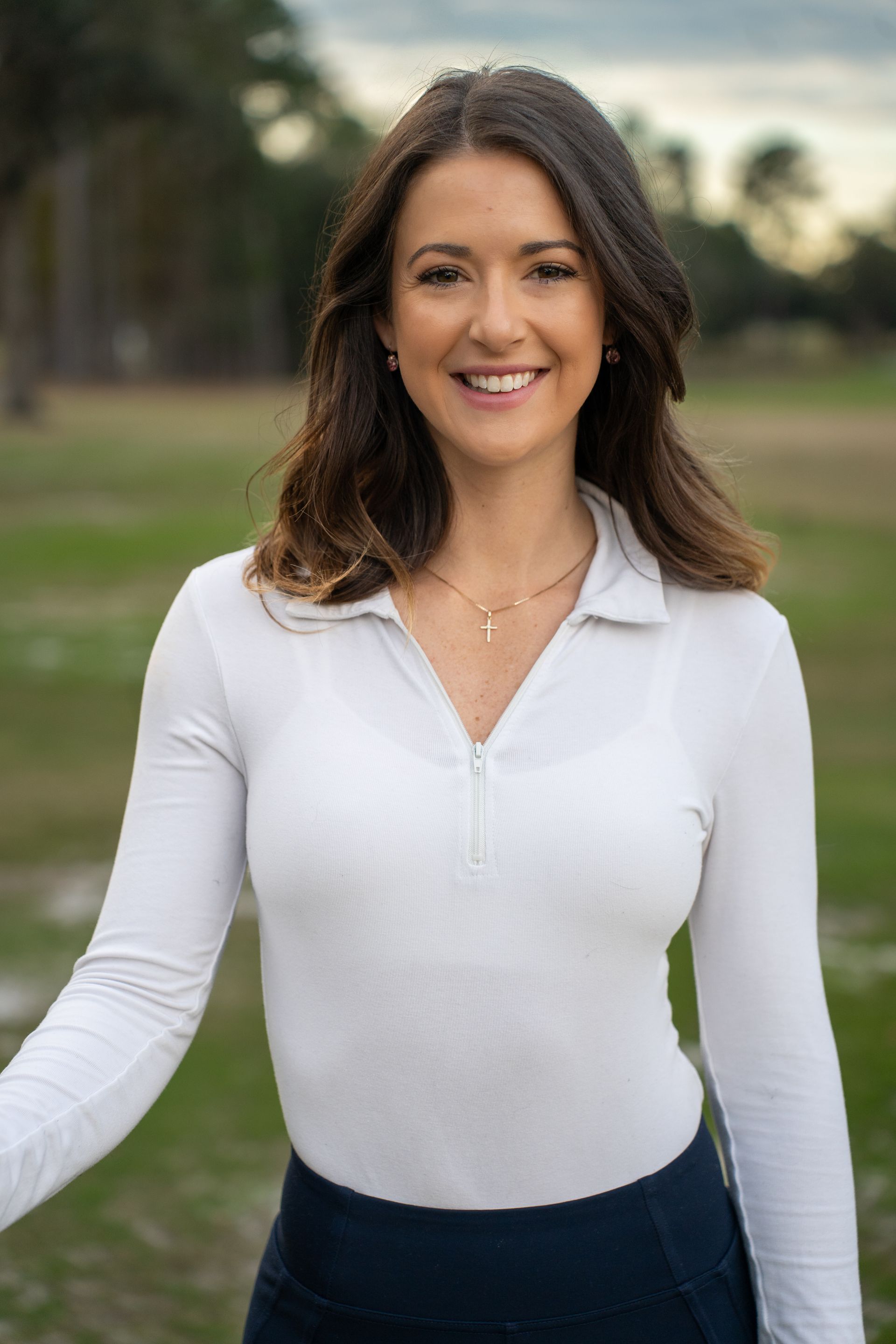 A woman in a white shirt and blue skirt is standing in a field.