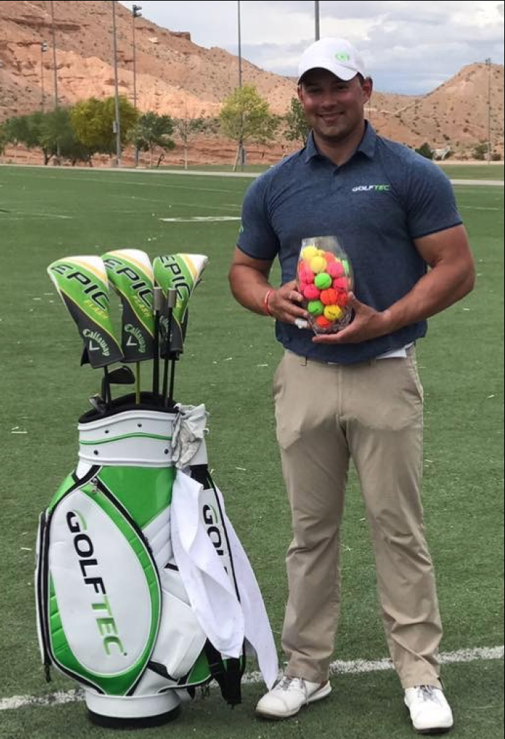 A man is standing next to a golf bag and holding a bag of golf balls.