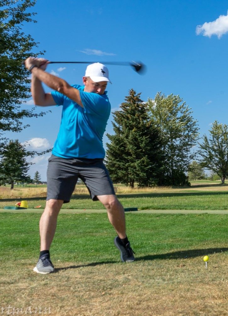 A man is swinging a golf club on a golf course.