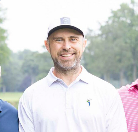 A man wearing a hat and a white shirt is smiling for the camera.