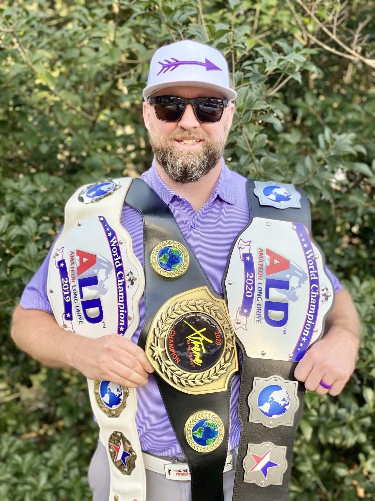 A man is holding two championship belts in his hands.