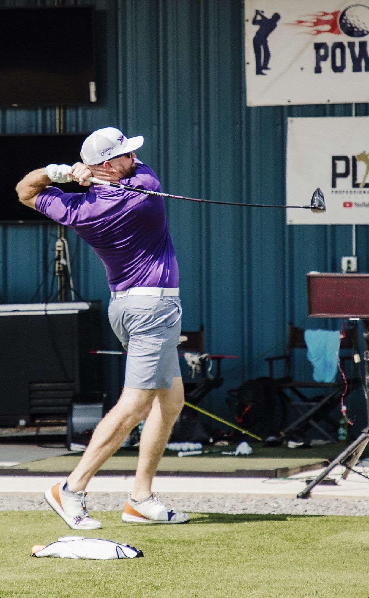A man in a purple shirt is swinging a golf club.