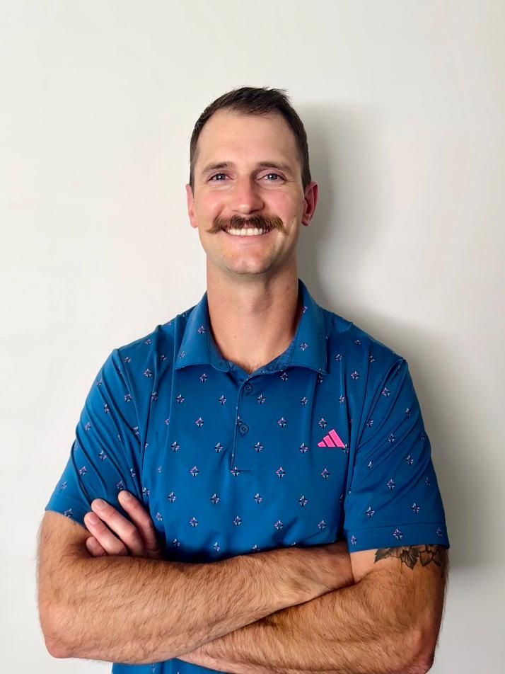 A man with a beard is wearing a black and white polo shirt.