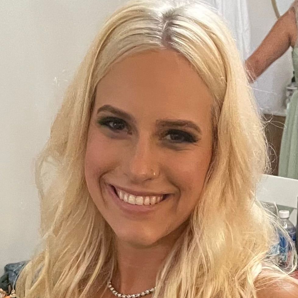 A close up of a woman with blonde hair smiling.