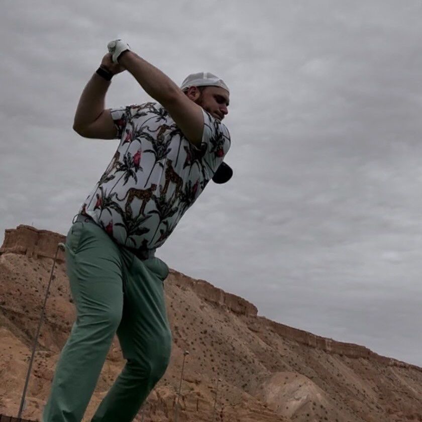 A man in a floral shirt is swinging a golf club