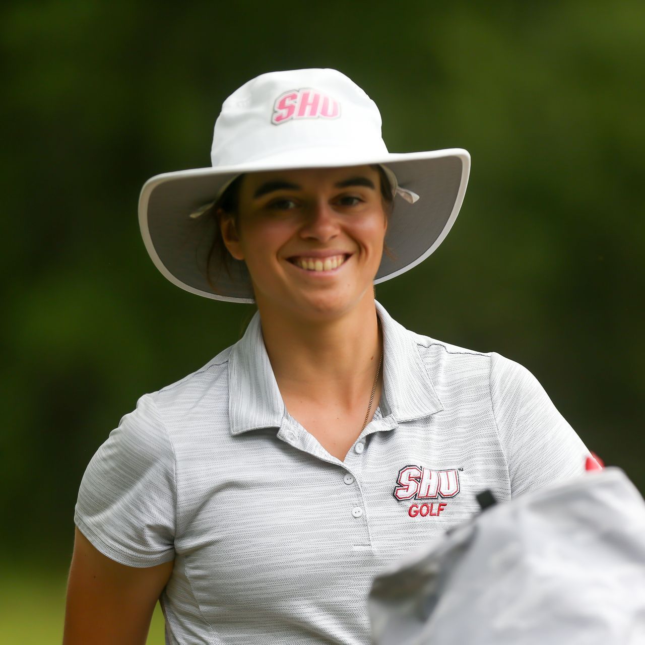 A woman wearing a white hat and a shirt with the word golf on it