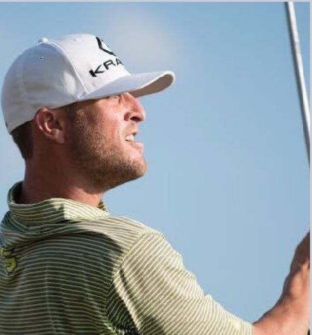 Golfer in white cap and striped shirt, looking up and right, holding a club.