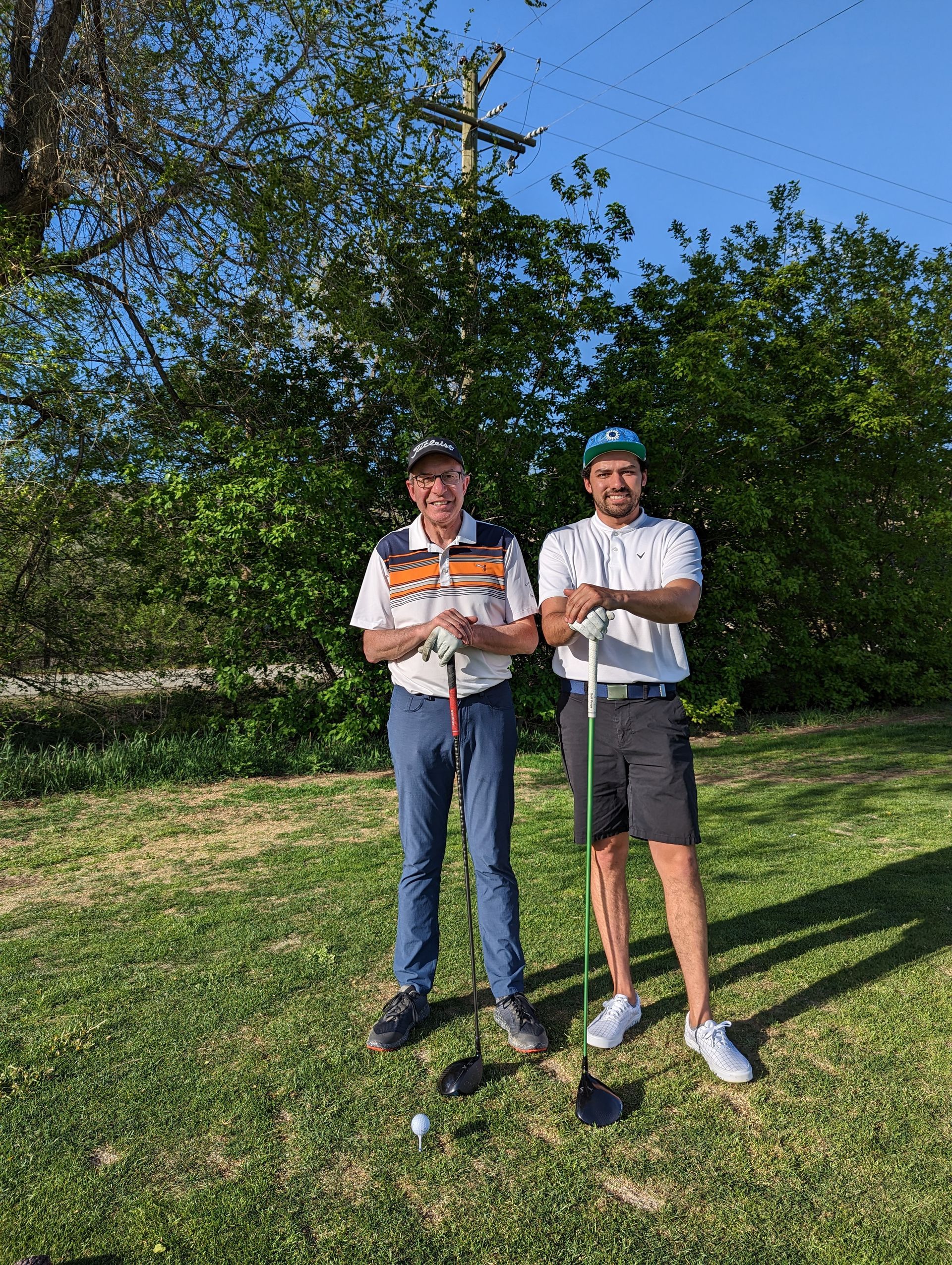 Two men holding golf clubs on a grassy course.