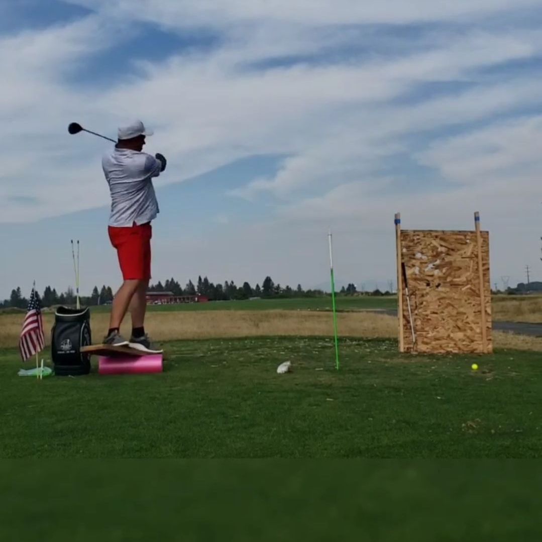 A man is swinging a golf club on a golf course
